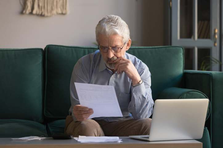 Serious mature man sitting on couch analyzing contract