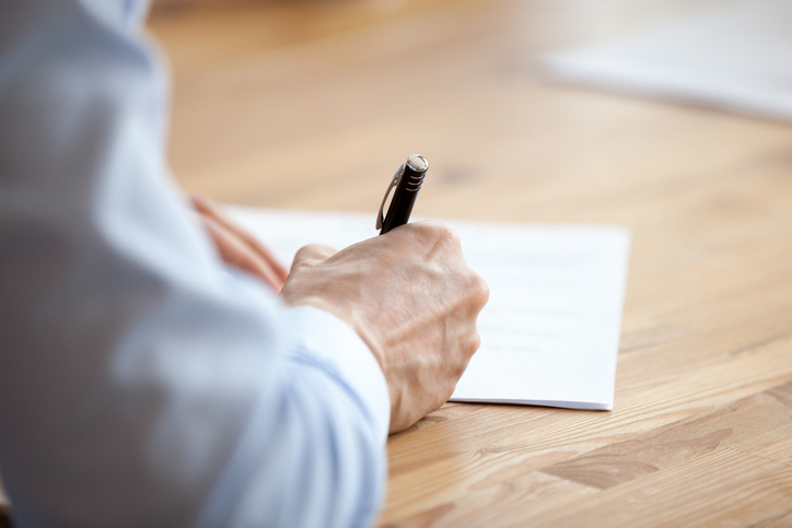 Man hand holding pen, writing a demand letter